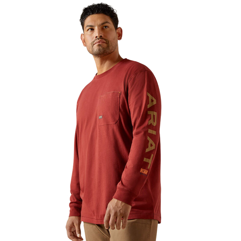 Man wearing a red long-sleeve shirt with 'Ariat' branding on a beige background