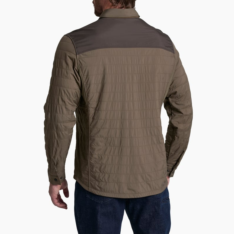 A man viewed from the back wearing a two-tone quilted jacket in brown and dark gray, paired with dark blue jeans, against a plain white background.