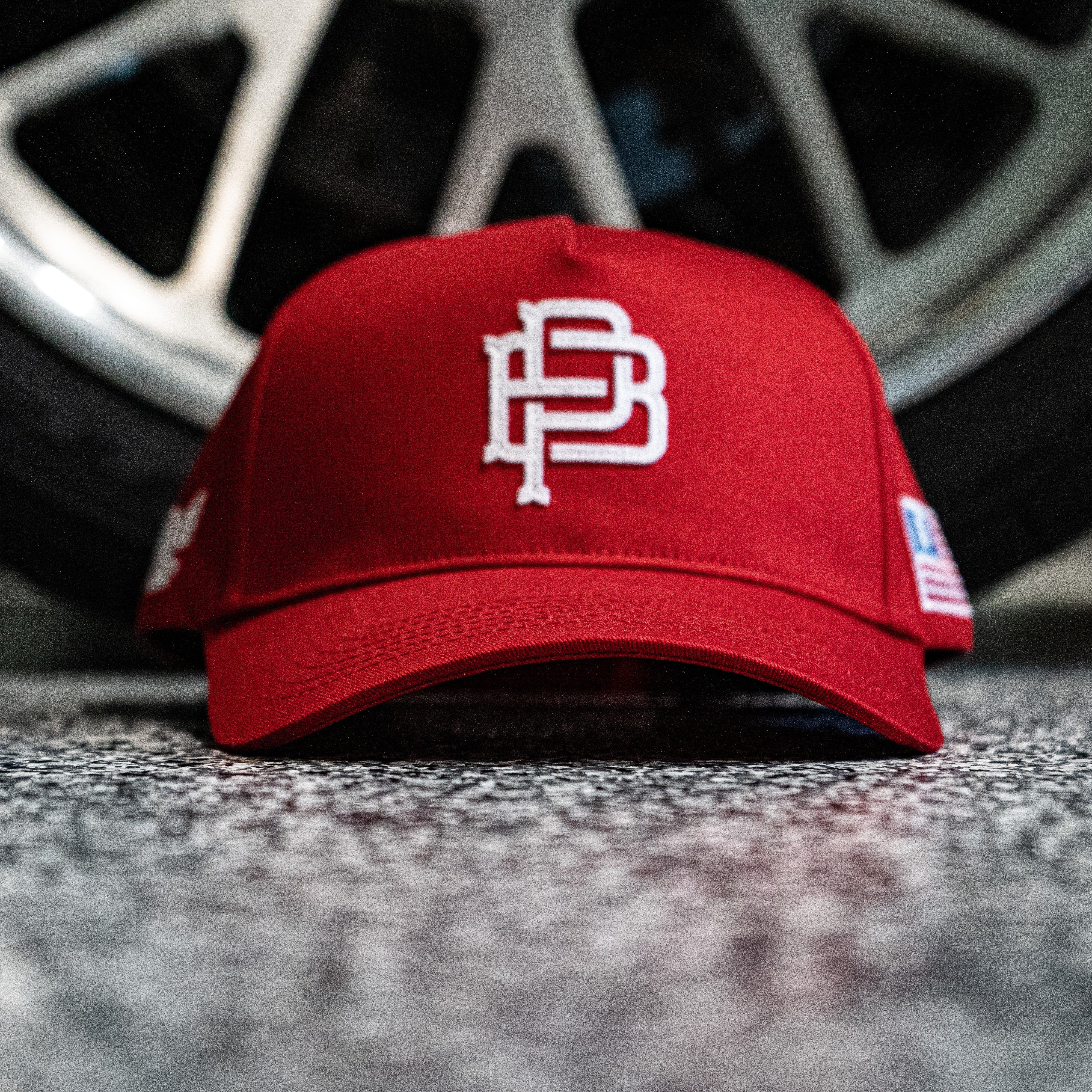 Red cap with a logo on a textured surface with a blurred wheel in the background