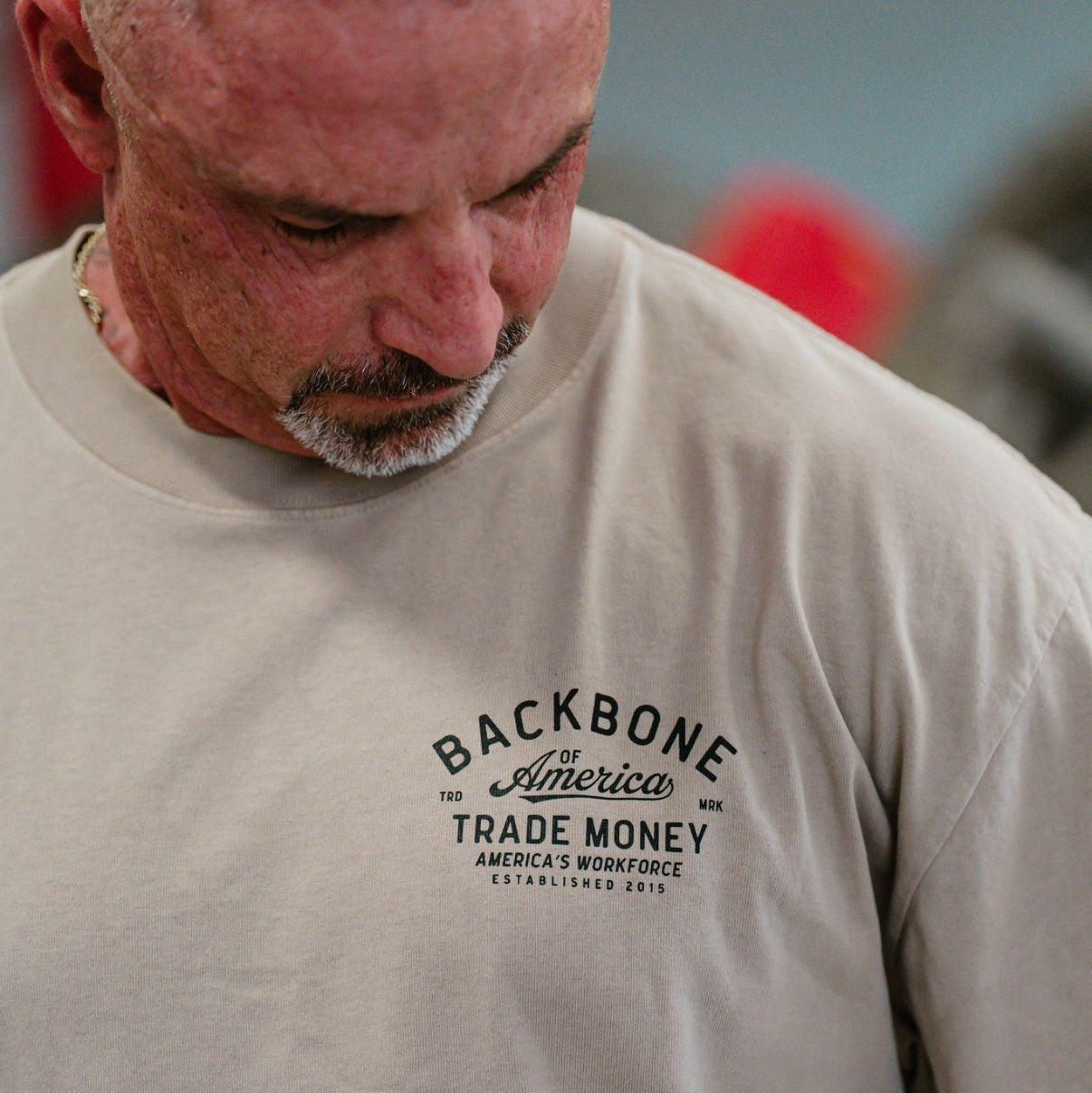 Man wearing a beige t-shirt with 'Backbone of America' text