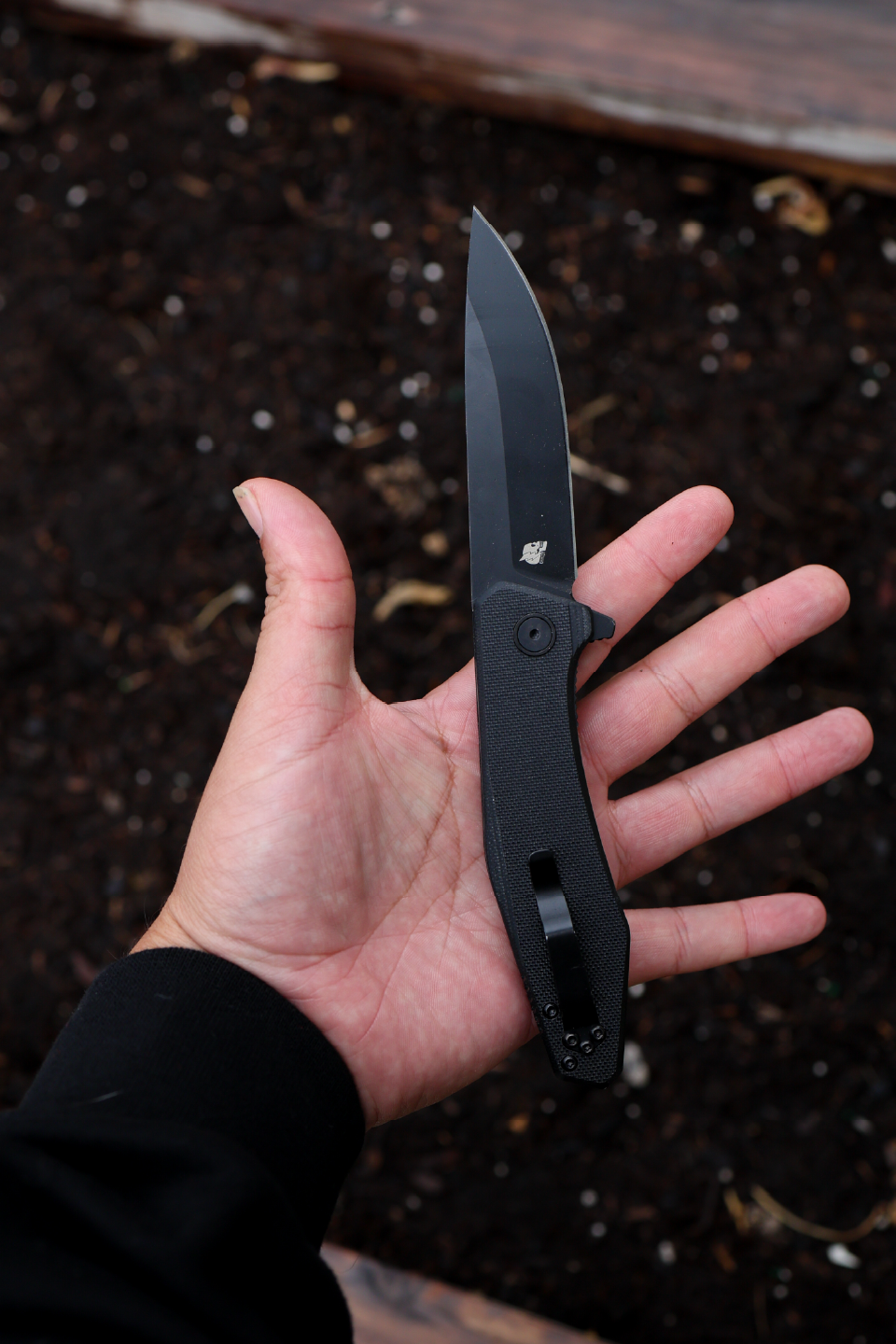 Crimson × Purpose-Built M6 Folder held open in hand, Crimson logo side