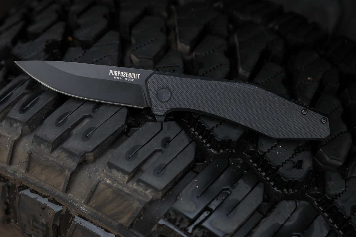 Crimson × Purpose-Built M6 Folder on a truck tire, Purpose-Built logo on the blade